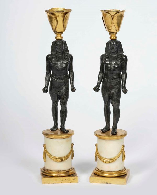 Coppia di piccoli candelieri in bronzo dorato e patinato con figure di Antinoo-Osiride. Arte neoclassica. Fonditore del XVIII-XIX secolo