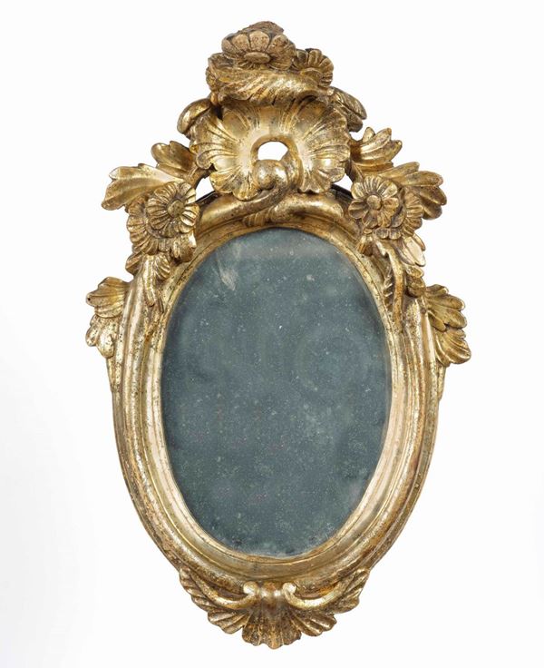 Specchiera ovale in legno intagliato e dorato a mecca. XVIII secolo