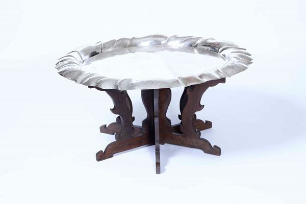 Tavolino composto da un grande vassoio in metallo argentato su supporto in legno sagomato
