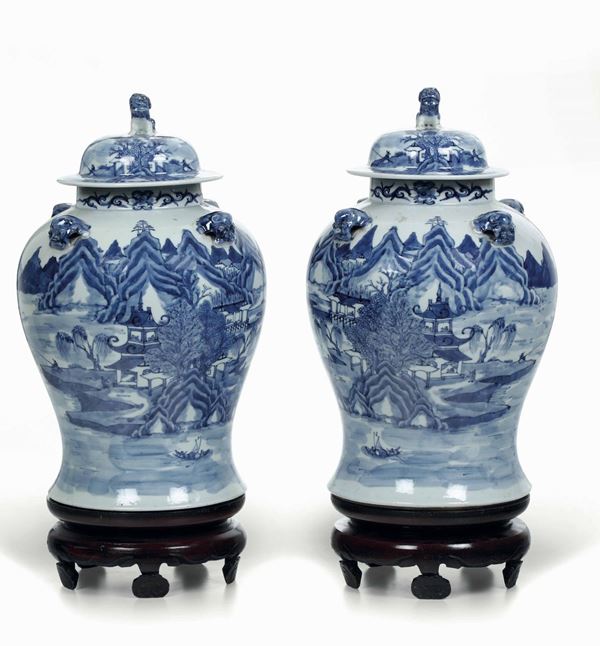 Coppia di potiches in porcellana bianca e blu con raffigurazioni di paesaggi, mascheroni e presa del coperchio a foggia di Cani di Pho, Cina, Dinastia Qing, XIX secolo
