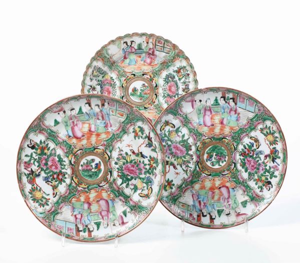 Lotto composto da tre piatti in porcellana Famiglia Rosa con scene di vita comune entro riserve e decori floreali, Canton, Cina, Dinastia Qing, XIX secolo