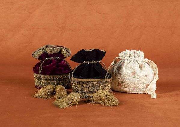 Due borsette a sacchetto in velluto con passamanerie dorate e nappe e una borsetta sacchetto in tela ricoperta con perline bianche e fiori ricamati.