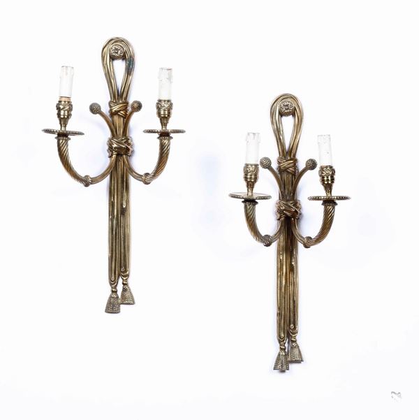 Coppia di appliques a due luci in metallo dorato in forma di nastri. XIX-XX secolo