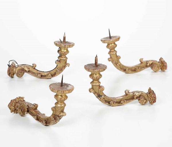 Quattro appliques ad una luce in legno intagliato e dorato. XVIII secolo