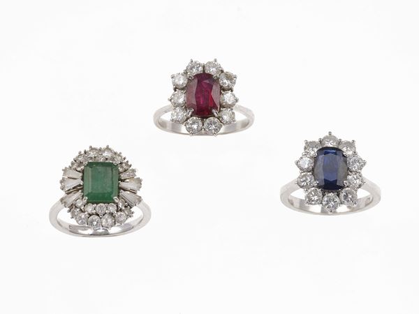 Tre anelli con rubino, zaffiro, ameraldo e diamanti a contorno