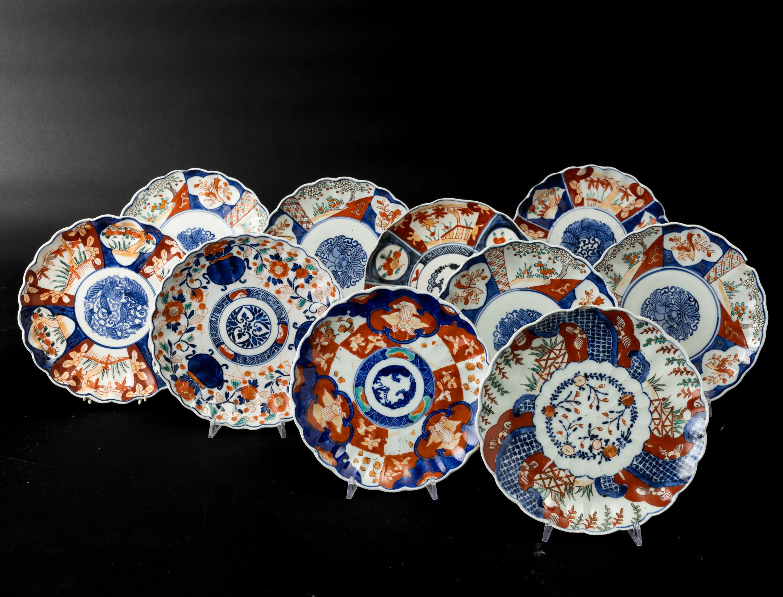 Giappone, lotto di dieci piatti in porcellana Imari con decorazioni floreali entro riserve, perio...