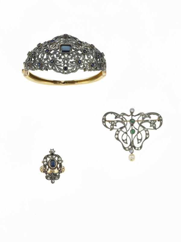 Lotto composto da una spilla, un anello ed un bracciale rigido con diamanti di vecchio taglio, zaffiri ed uno smeraldo