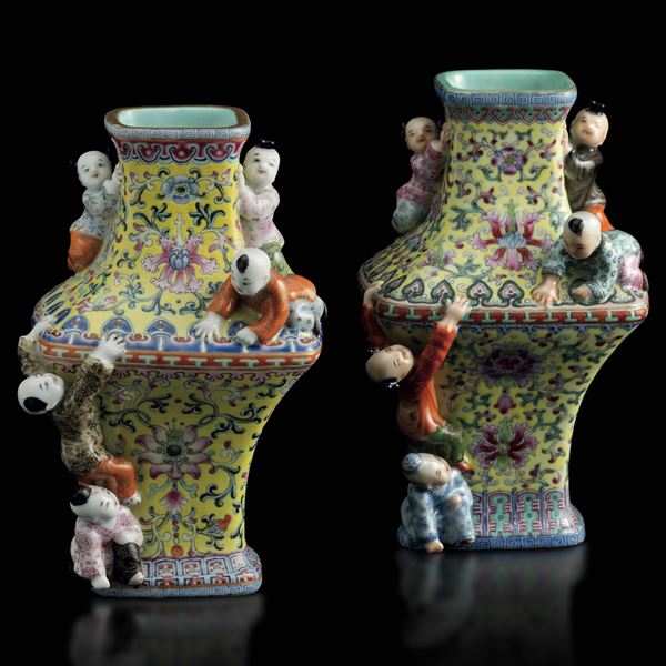 Coppia di vasi in porcellana a smalti policromi con decori floreali e figure di fanciulli a rilievo,  [..]