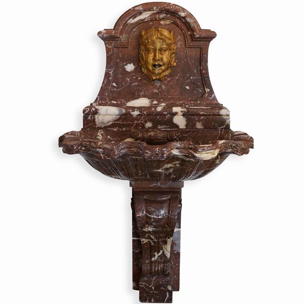 Fontana in marmo rosso con mascherone dorato. Manifattura italiana del XX secolo