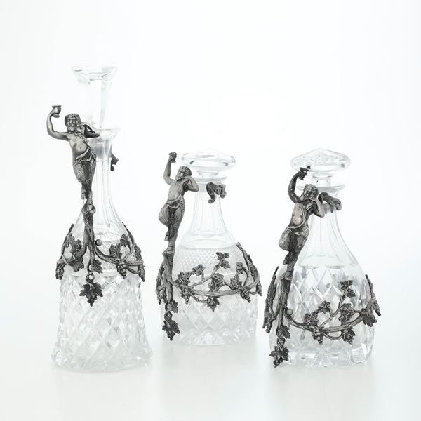 Tre bottiglie in cristallo con montatura in metallo argentato. XIX secolo