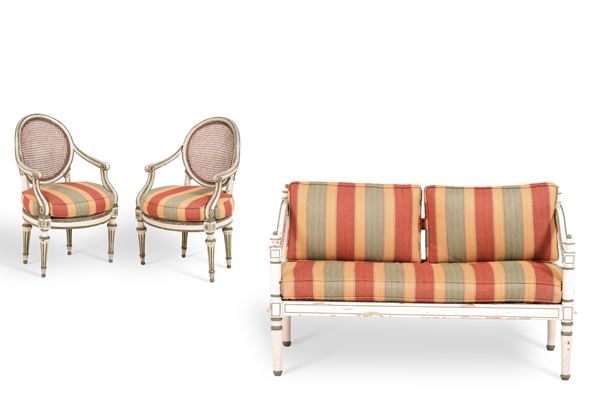 Piccolo divanetto e coppia di poltrone in legno dipinto. XIX secolo