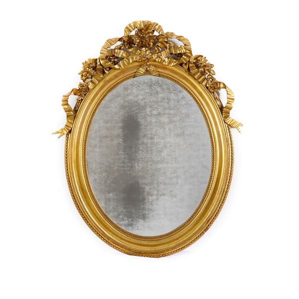 Specchiera ovale dorata in legno intagliato e pastiglia. XIX-XX secolo