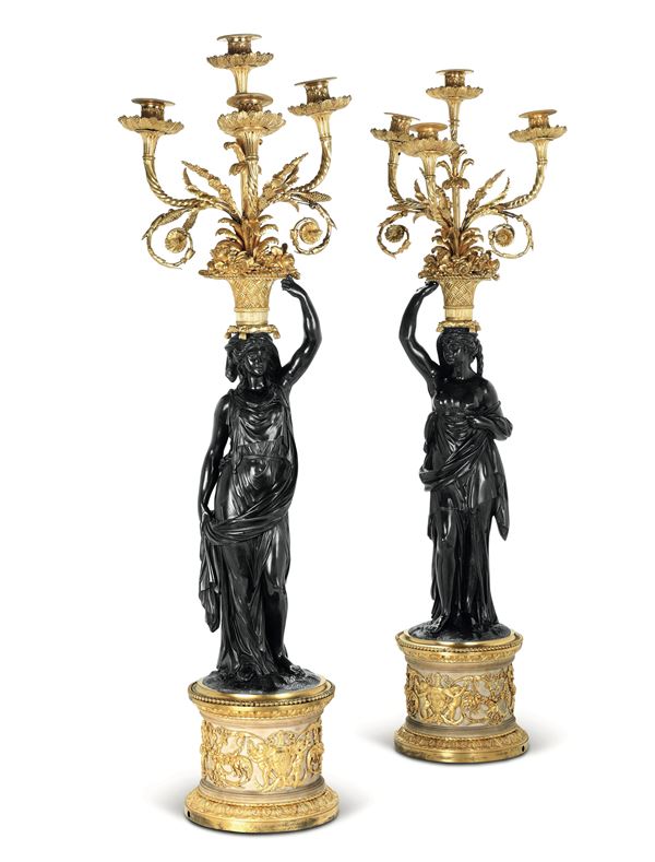 Coppia di imponenti candelabri a quattro luci in bronzo patinato e dorato. Dal modello di Francois Remond, Francia