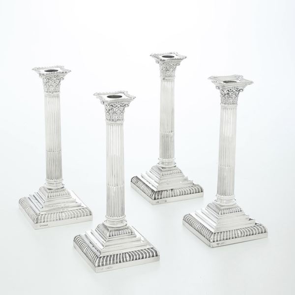 Quattro candelieri in argento a foggia di colonne corinzie. Tre con marchio dell'argentiere Goldsmiths  [..]