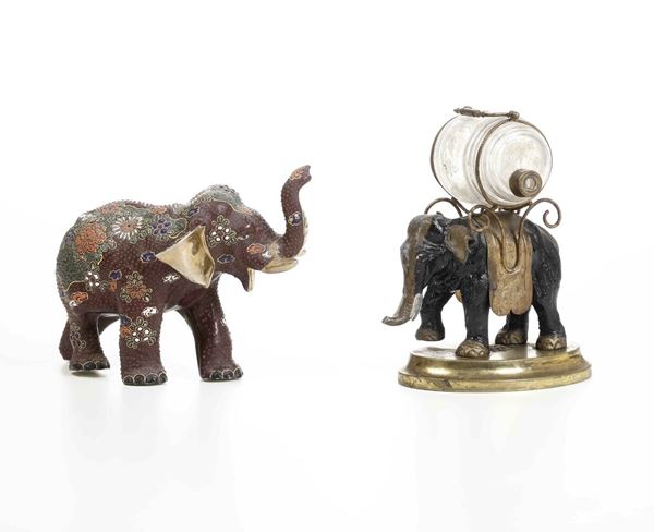 Due elefanti uno in porcellana dipinta (XX secolo) e uno in metallo con barilotto in vetro decorato