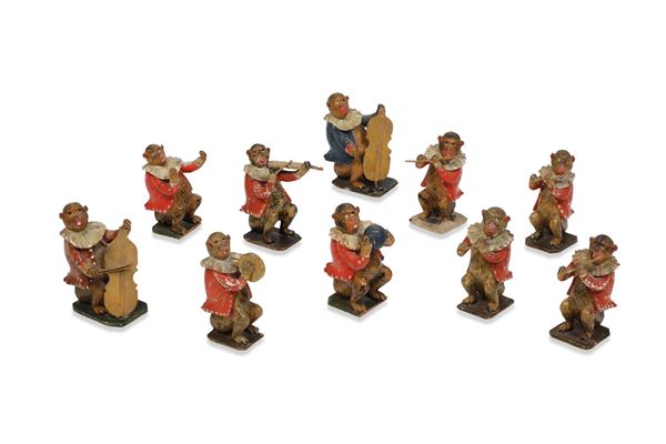 Lotto di dieci sculturine raffiguranti scimmie suonatirici in legno laccato. XVIII-XIX secolo