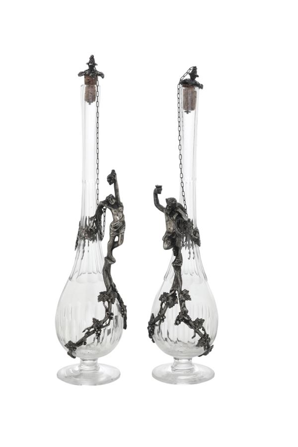 Due bottiglie in cristallo con manici a figure maschili in metallo. XX secolo.