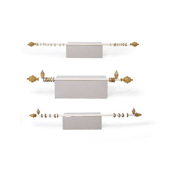 Tre bastoni per tende con pigne in legno intagliato e dorato