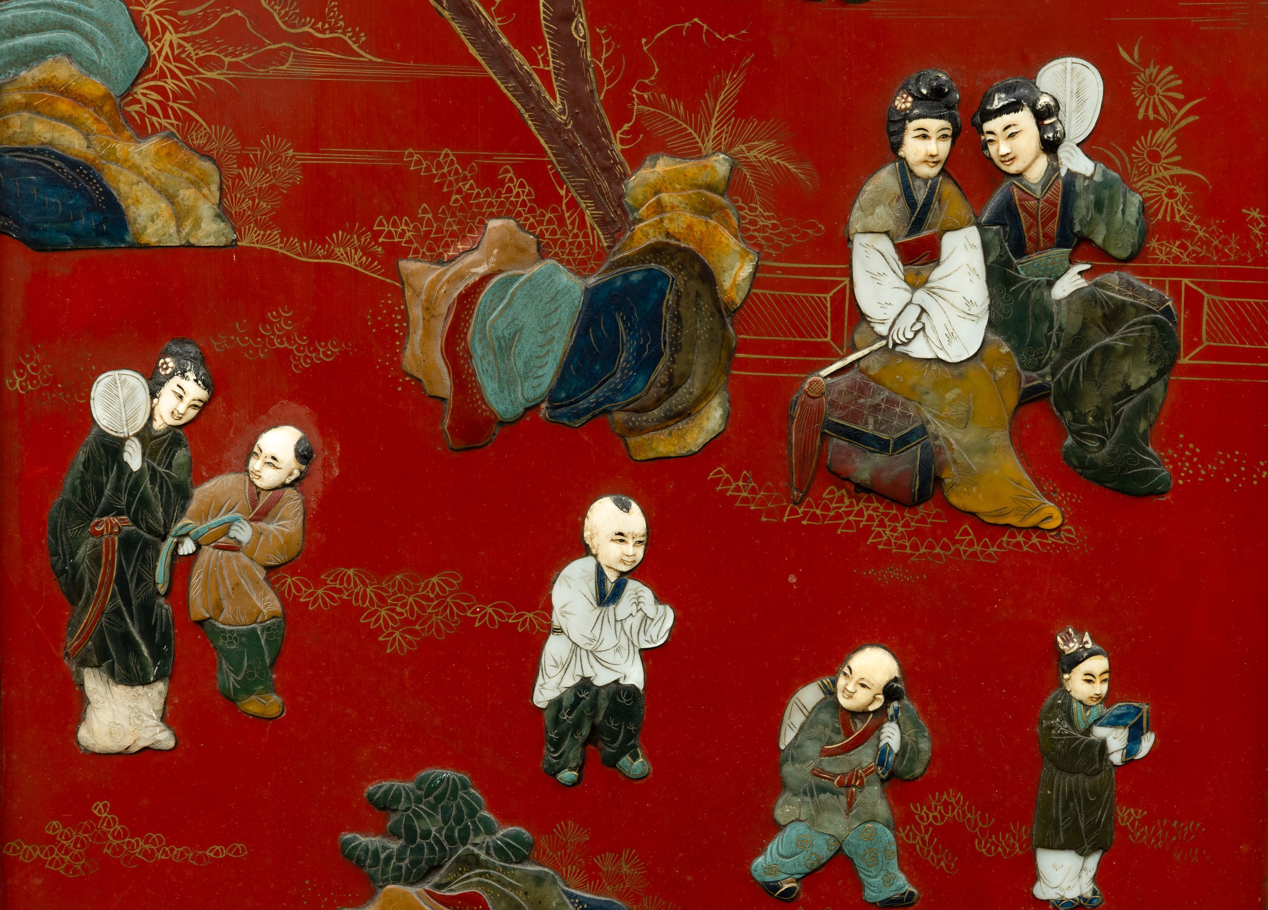 Paravento a tre ante in legno rosso laccato e applicazioni in pietre dure raffigurante scene di v...