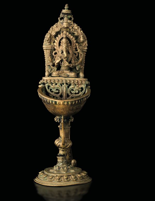 Lampada ad olio in bronzo dorato raffigurante Ganesh seduto su fior di lotto, decori naturalistici a rilievo e iscrizioni, India, XIX secolo