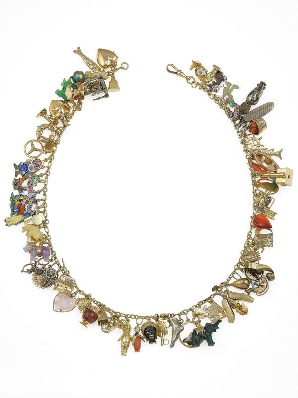 Gold and low-karat gold charms necklace. Thirteen charms signed Cartier