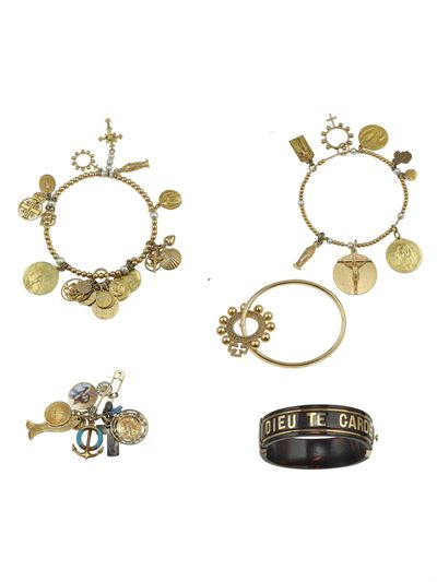 Lotto composto da quattro bracciali e una spilla con charms, in oro giallo 750/1000 e metalli mis...