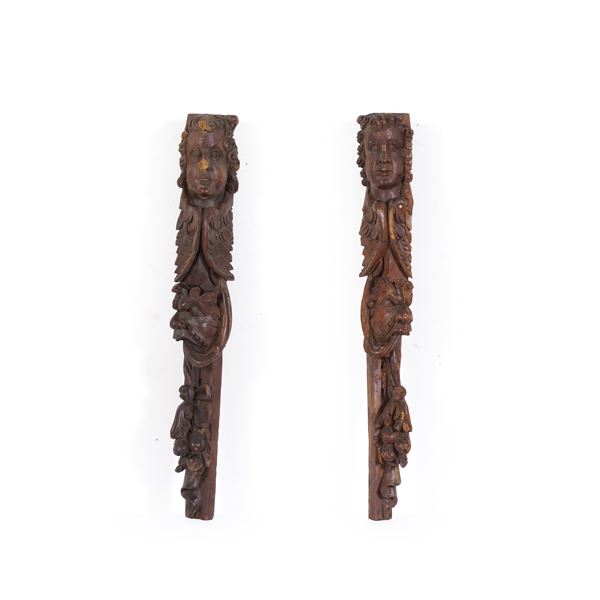 Due cariatidi in noce scuro intagliato a teste di angelo