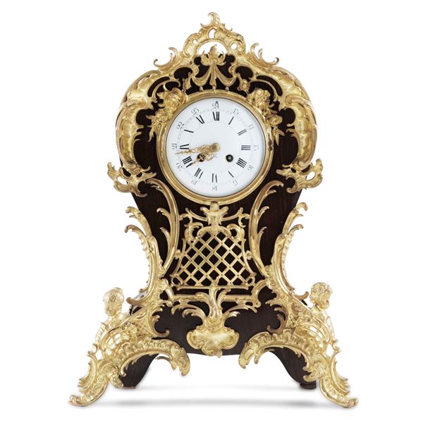 Pendola da tavolo in legno riccamente decorata. XIX secolo