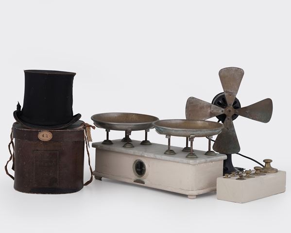 Una bilancia con base per i pesi (alcuni mancanti), un ventilatore, un cilindro entro custodia. XX secolo