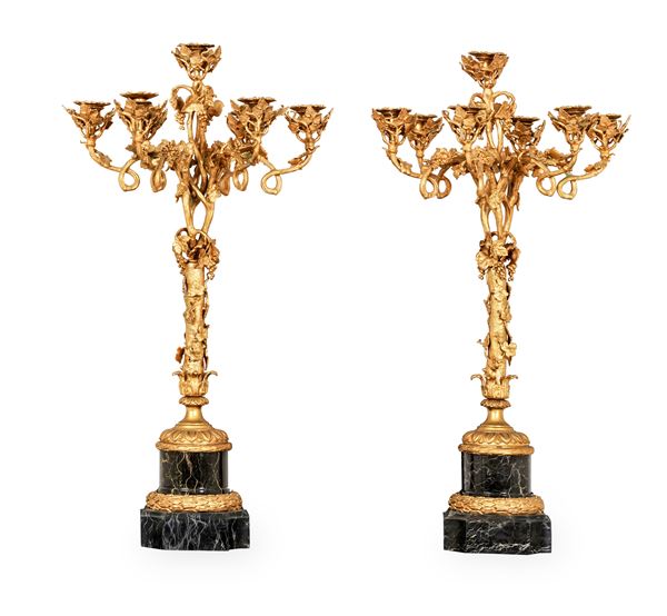 Coppia di candelabri a sette luci in bronzo dorato su basi in marmo nero. XX secolo