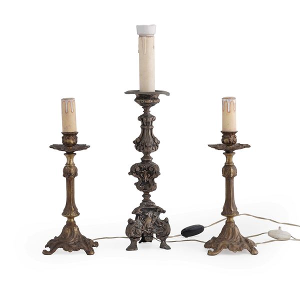 Lotto di una coppia di candelieri in metallo dorato, unito ad un reggicero a più ordini, in metallo sbalzato e argentato. Montate a luce elettrica. XIX secolo