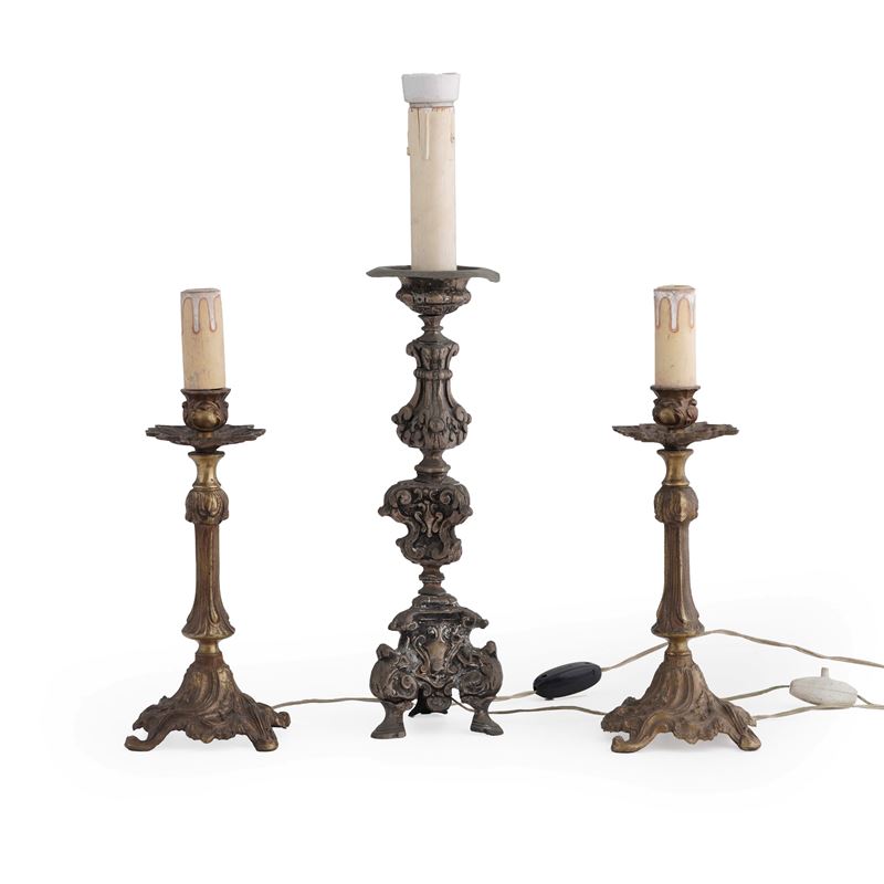 Lotto di una coppia di candelieri in metallo dorato, unito ad un reggicero a più ordini, in metallo sbalzato e argentato. Montate a luce elettrica. XIX secolo  - Auction Antiques - Cambi Casa d'Aste