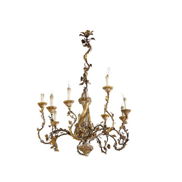 Lampadario di gusto settecentesco con fusto in legno intagliato e dorato e dieci bracci portaluce in ferro battuto