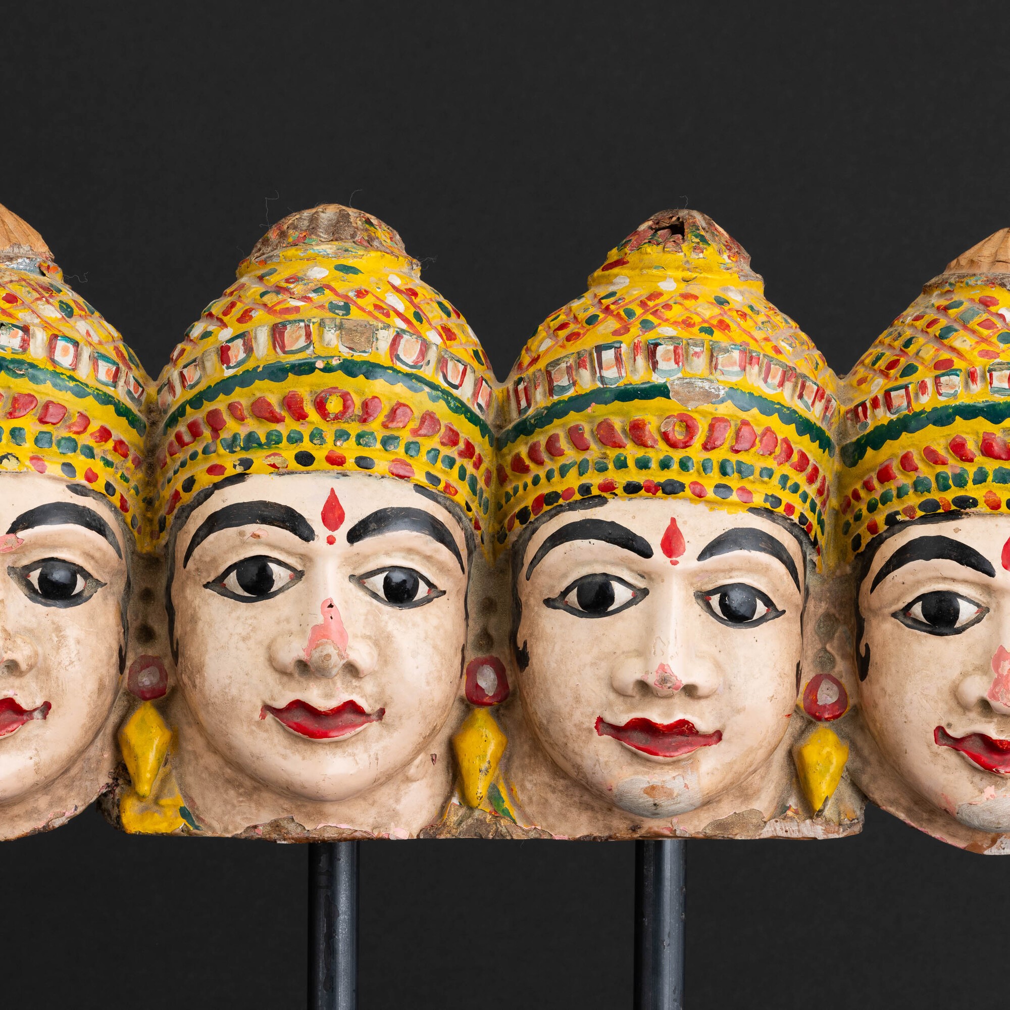 Gruppo di sette teste in legno scolpito e dipinto, India, XIX secolo