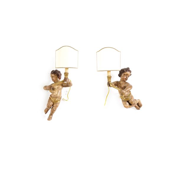 Coppia di putti reggicero in legno intagliato e laccato. XIX-XX secolo