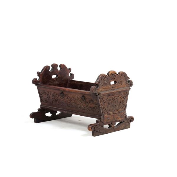 Antica culla in legno intagliato.