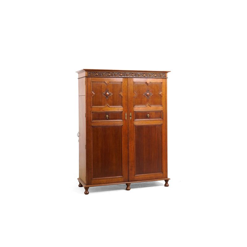 Armadio a due ante pannellate con cappello intagliato a tralci di vite. XX secolo  - Auction Antiques - Cambi Casa d'Aste