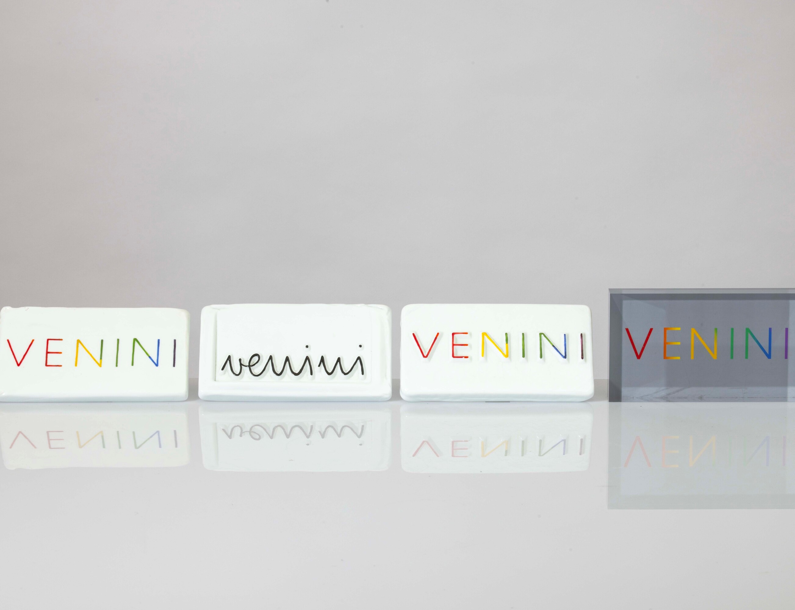 Venini, Lotto di quattro placche pubblicitarie in vetro lattimo e plexiglass, cm 16x9