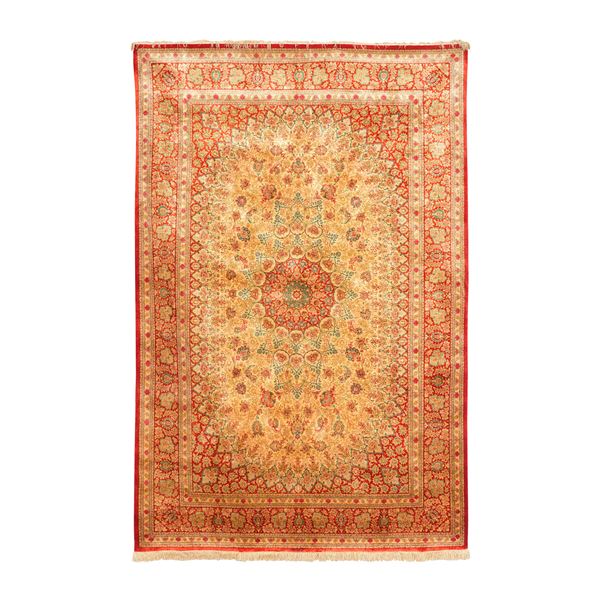 Tappeto Persia XX secolo in seta, campo beige con medaglione rosso. Firmato nella testata superiore.