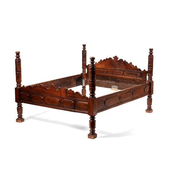 Letto a colonne in noce intagliato. XIX-XX secolo