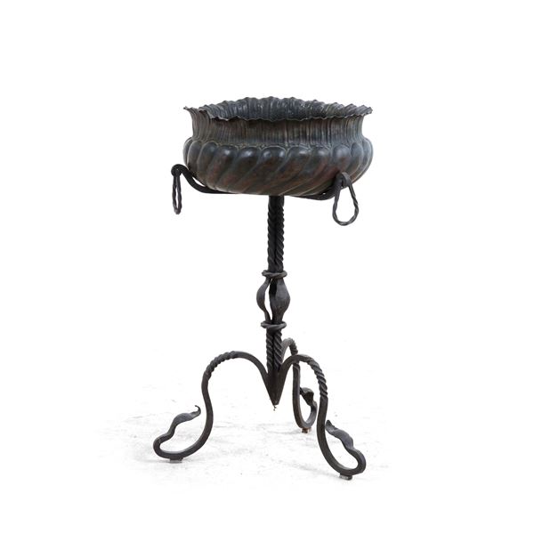 Una fioriera in rame con base tripode