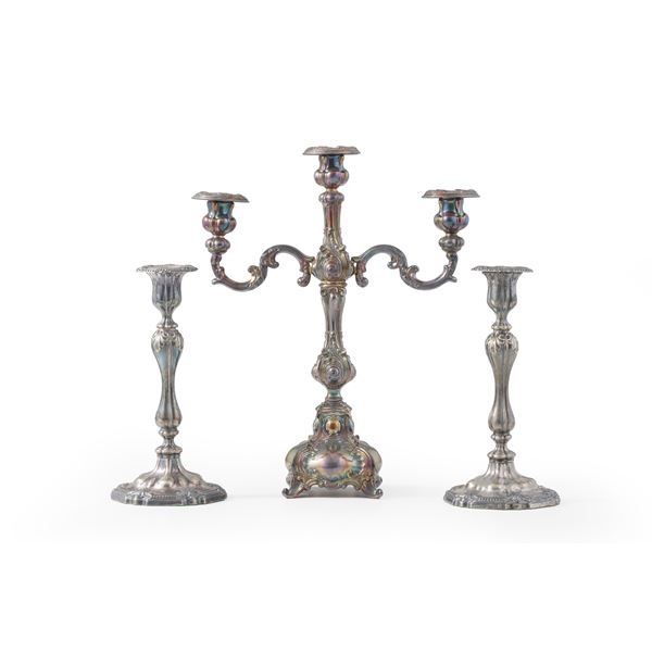 Lotto composto da un candeliere a due fiamme e una coppia di candelieri a una fiamma in metallo argentato