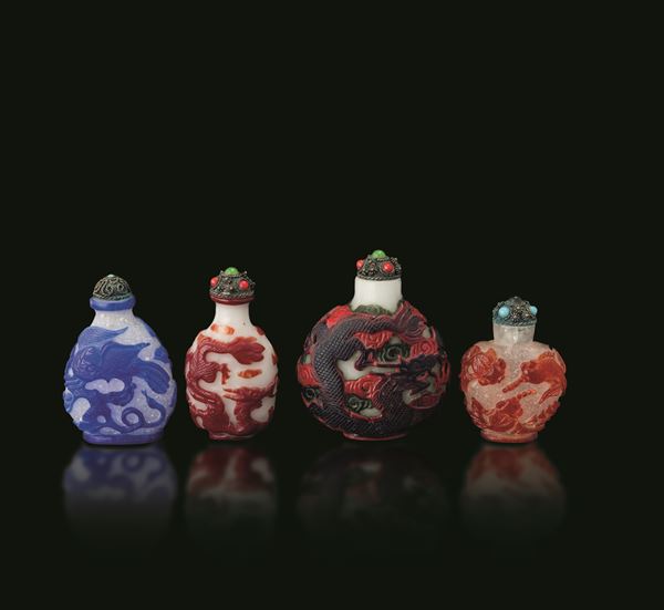 Lotto composto da quattro snuff bottle in vetro di Pechino con decori a rilievo raffiguranti draghi e inserti di pietre dure, Cina, XIX e XX secolo