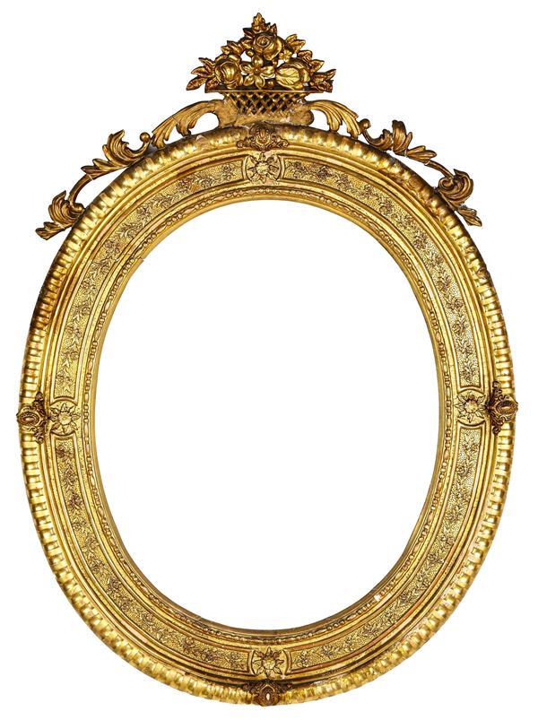 Cornice ovale dorata con cimasa decorata a fiori e foglie. XIX secolo