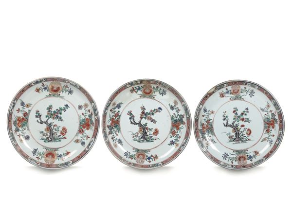 Tre piatti in porcellana nei colori della Famiglia Verde con decori floreali e albero in fiore centrale, Cina, XX secolo