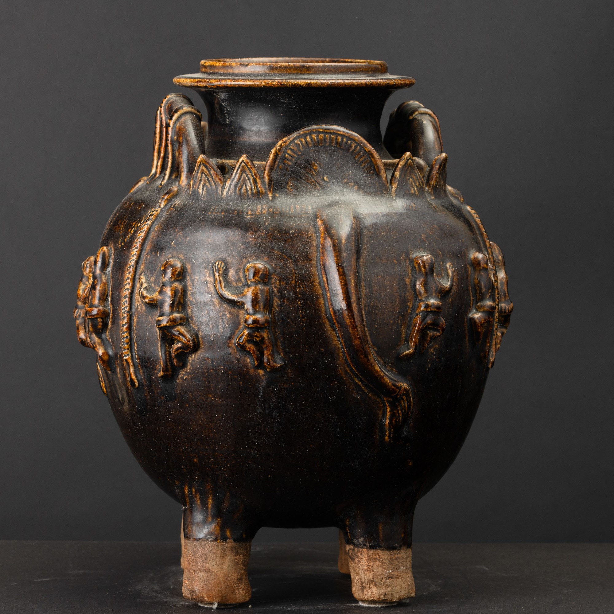 Arte Khmer, Vaso in terracotta invetriata a fondo marrone con testa di elefante e figure a riliev...
