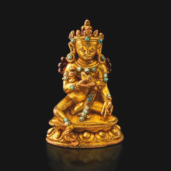 Piccola figura di divinità seduta su fiore di loto con tracce di policromia e inserti di pietre dure in bronzo dorato, Tibet, XIX secolo