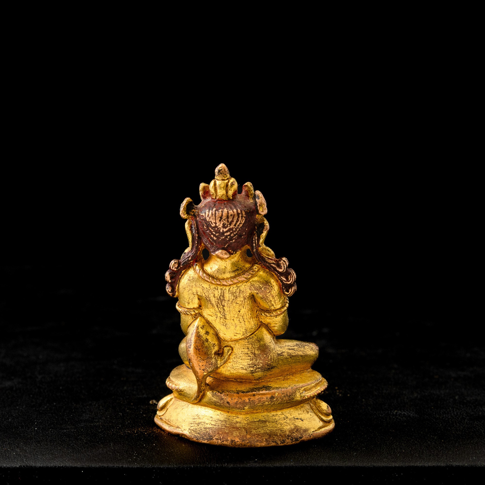 Tibet, piccola figura di divinità seduta su fiore di loto, bronzo dorato con tracce di policromia...