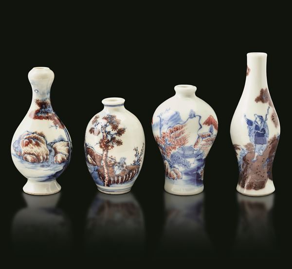 Lotto composto da quattro snuff bottle in porcellana a fondo bianco con decori in blu cobalto e rosso ferro, raffiguranti scene paesaggistiche, Cina, Dinastia Qing, XX secolo