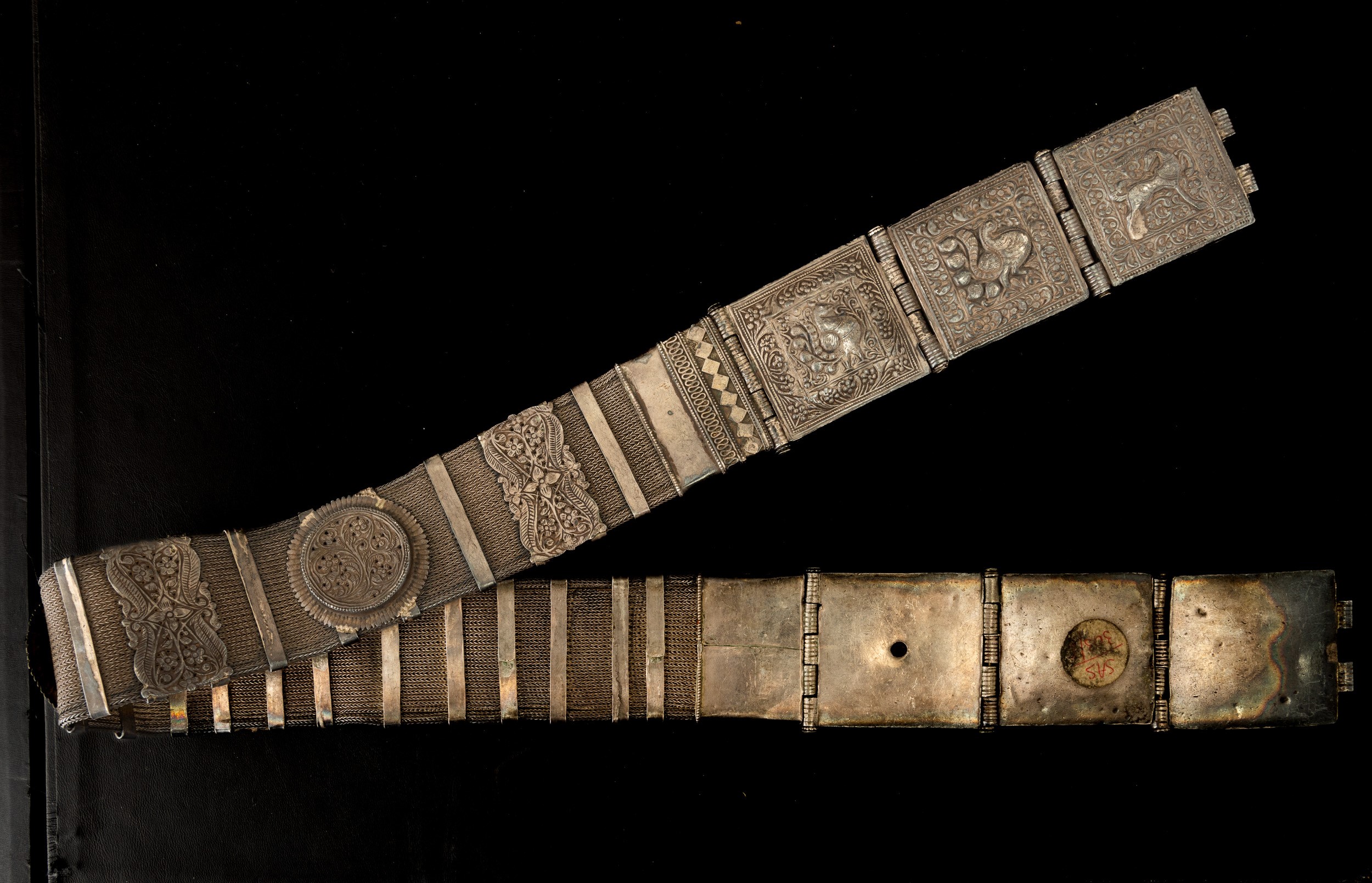 Tibet, Cintura in metallo argentato con decorazioni a rilievo e catena intrecciata,  XIX secolo